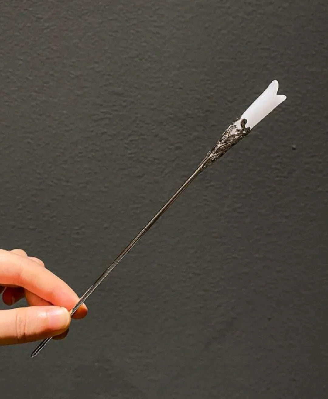 Hand holding a decorative arrow against a dark gray background